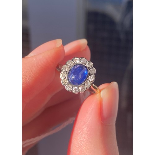 24 - An early 20th century 18ct gold, sapphire cabochon and diamond cluster ring, the sapphire measuring ... 