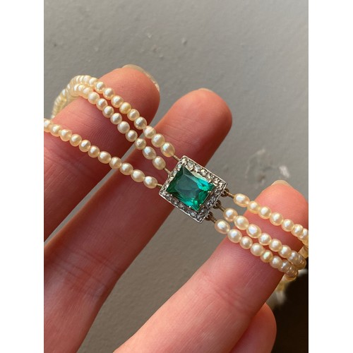 33 - An Edwardian three strand seed pearl bracelet with central rectangular bluish-green tourmaline surro... 