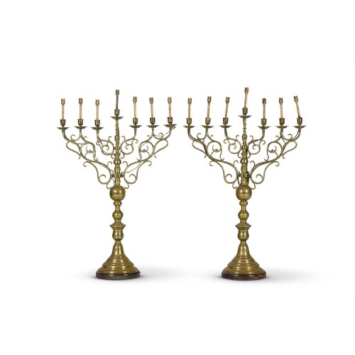 A pair of Dutch seven light brass candelabra, late 19th century, with scroll arms on baluster stems and domed bases, adapted for electricity 97.5cm high overall, 64cm wide across the arms
