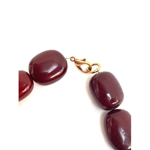 27 - A vintage cherry amber bakelite bead necklace, the beads ranging from 18mm to 22mm, fastening with a... 
