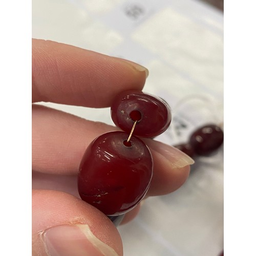 27 - A vintage cherry amber bakelite bead necklace, the beads ranging from 18mm to 22mm, fastening with a... 