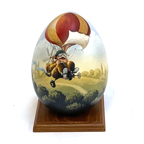 395 - A hand painted wooden egg by JMF Robuchon, decorated with a man on bicycle, 18cmH