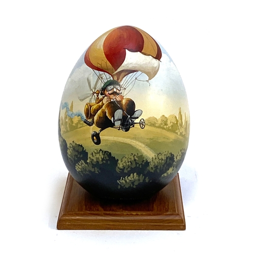 395 - A hand painted wooden egg by JMF Robuchon, decorated with a man on bicycle, 18cmH