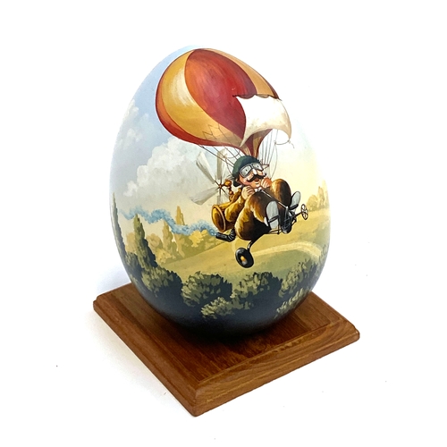395 - A hand painted wooden egg by JMF Robuchon, decorated with a man on bicycle, 18cmH