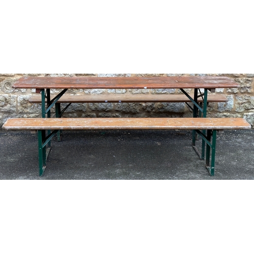 1351 - A narrow pine trestle table, on folding green metal base, 216x50x76cm; together with two matching fo... 