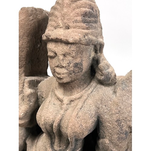 1240 - An Indian carved sandstone statue depicting the god Surya flanked by diminutive attendants, 47cmH ex... 