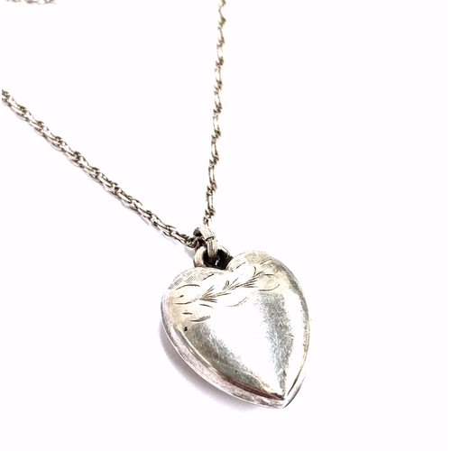 35 - An early 20th century silver puffy heart pendant on a silver chain, the heart with engraved detail, ... 