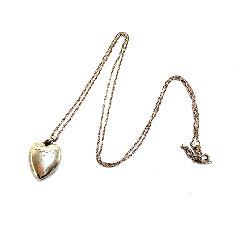 35 - An early 20th century silver puffy heart pendant on a silver chain, the heart with engraved detail, ... 