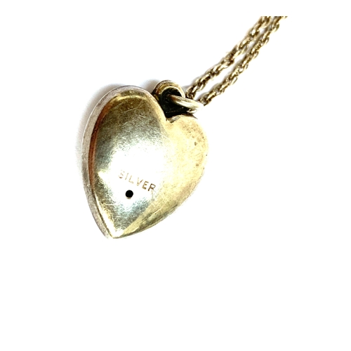 35 - An early 20th century silver puffy heart pendant on a silver chain, the heart with engraved detail, ... 
