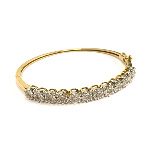 62 - A 14ct gold and diamond cluster bangle, 15g