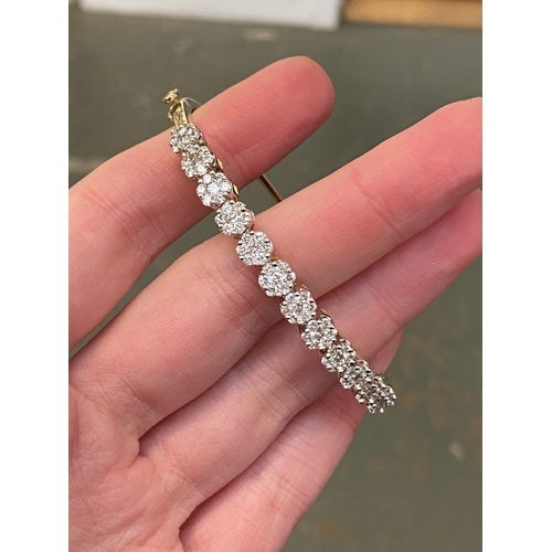 62 - A 14ct gold and diamond cluster bangle, 15g
