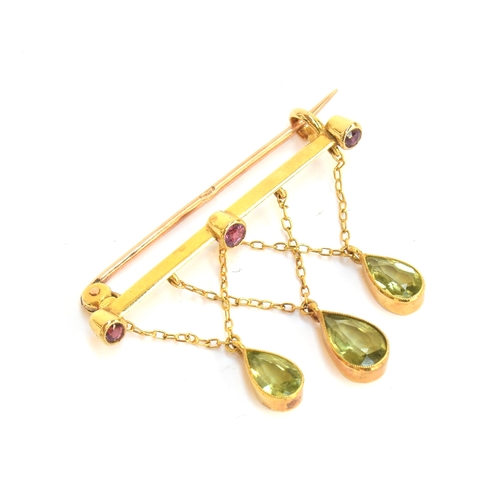 14 - An Edwardian 9ct gold, ruby and peridot bar brooch, the three pear cut peridots suspended from chain... 