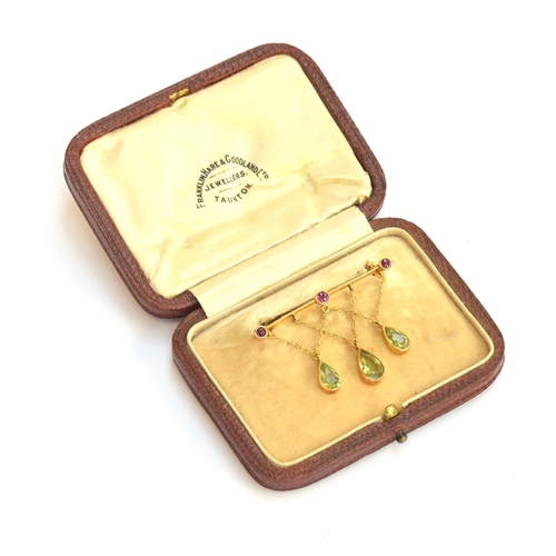 14 - An Edwardian 9ct gold, ruby and peridot bar brooch, the three pear cut peridots suspended from chain... 