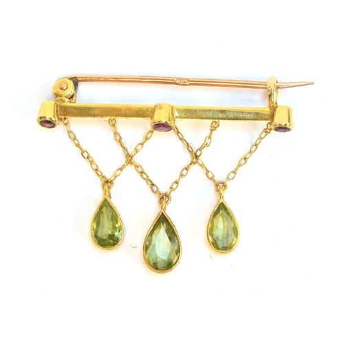 14 - An Edwardian 9ct gold, ruby and peridot bar brooch, the three pear cut peridots suspended from chain... 