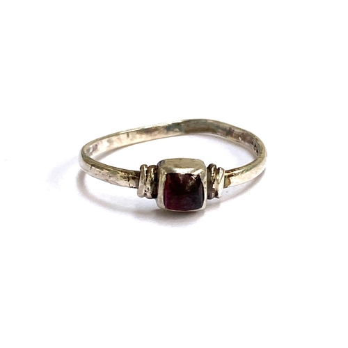 107 - A Medieval style silver ring set with a garnet cabochon in a rubover setting, size Q, 1.4g