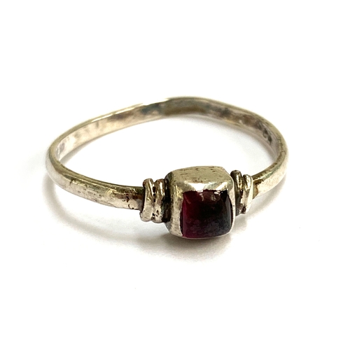 107 - A Medieval style silver ring set with a garnet cabochon in a rubover setting, size Q, 1.4g