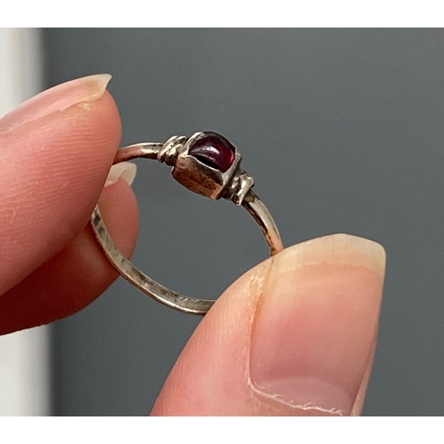 107 - A Medieval style silver ring set with a garnet cabochon in a rubover setting, size Q, 1.4g
