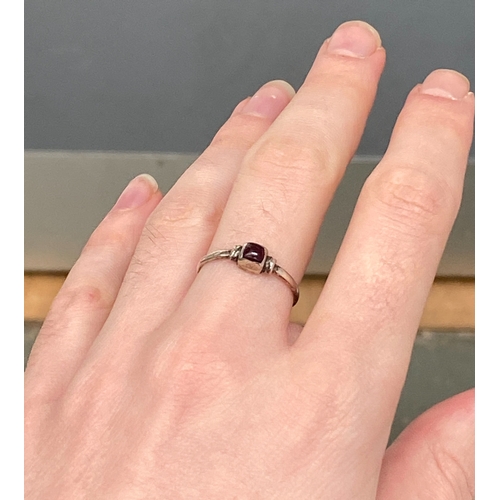 107 - A Medieval style silver ring set with a garnet cabochon in a rubover setting, size Q, 1.4g
