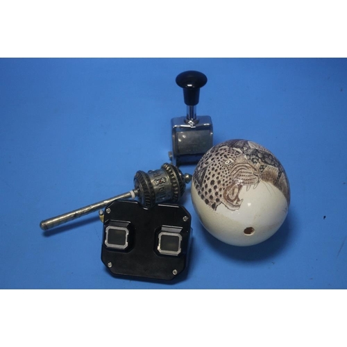 98 - A WHITE METAL TIBETAN PRAYER WHEEL and a carved ostrich egg depicting wild animals, a bakelite viewm... 