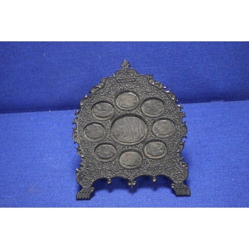 61 - AN ANTIQUE ANGLO INDIAN CARVED HARD WOOD STAND FOR MINIATURES, WITH 9 OVAL APERTURES FITTED WITH BRA... 