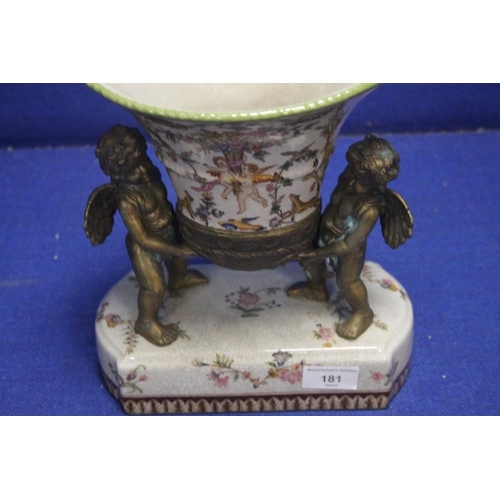 181 - A REPRODUCTION URN BEING HELD BY TWO BRONZE TYPE CHERUBS