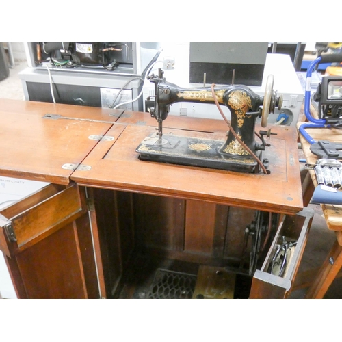 113 - An old Jones treadle operated sewing machine in mahogany cabinet