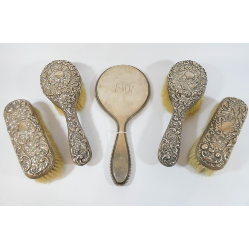 607 - Silver backed hairbrushes with embossed decoration and a silver backed hand mirror