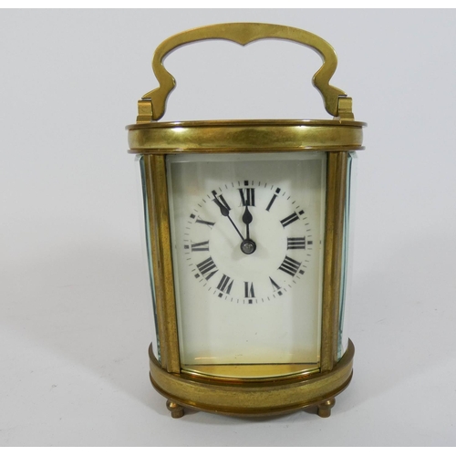 499 - A French gilt brass oval carriage clock with key, height with the handle up 15cms