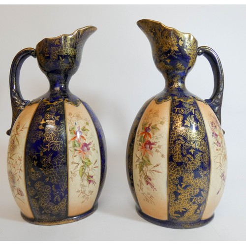 447 - A pair of late Victorian fushia decorated blue and gilt ewers, height 24cms