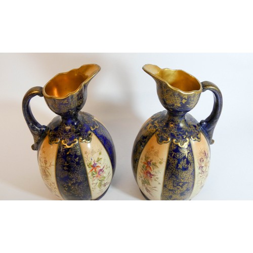 447 - A pair of late Victorian fushia decorated blue and gilt ewers, height 24cms