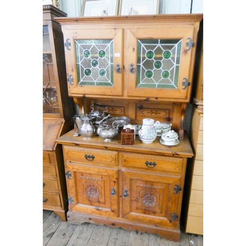 117 - A pine kitchen dresser with glazed lead light doors, drawers and cupboards under with carved panels.... 