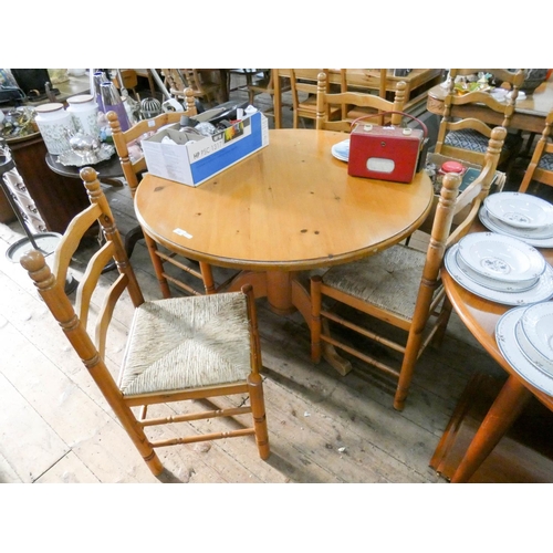 95 - Circular pine single pillar dining table and four matching ladder back chairs with rush seats