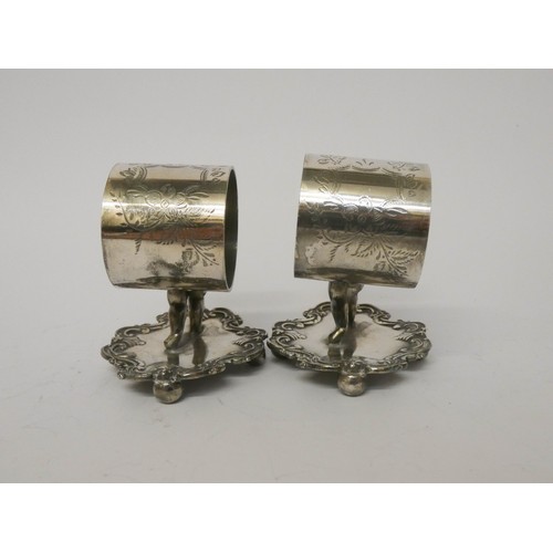 535 - Ten silver plate napkin ring holders supported by cherubs on fancy bases