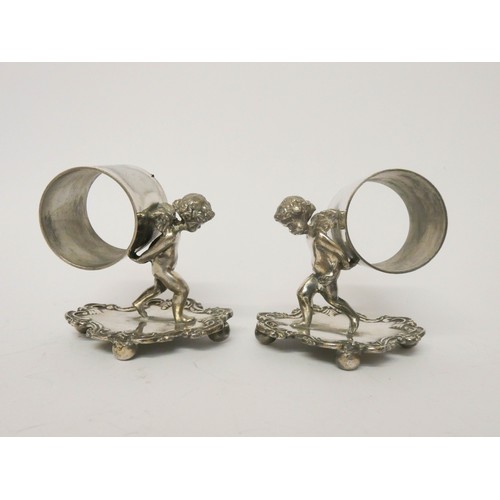 535 - Ten silver plate napkin ring holders supported by cherubs on fancy bases