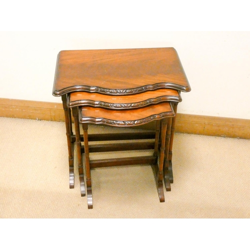 763 - A nest of three flame mahogany coffee tables with shaped fronts standing on fine turned legs