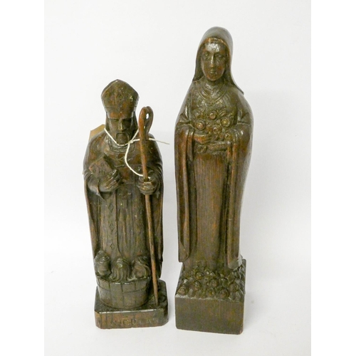 887 - A Black Forest style carved wooden figure of St Nicholas and another of lady saint with roses, the l... 