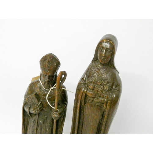 887 - A Black Forest style carved wooden figure of St Nicholas and another of lady saint with roses, the l... 