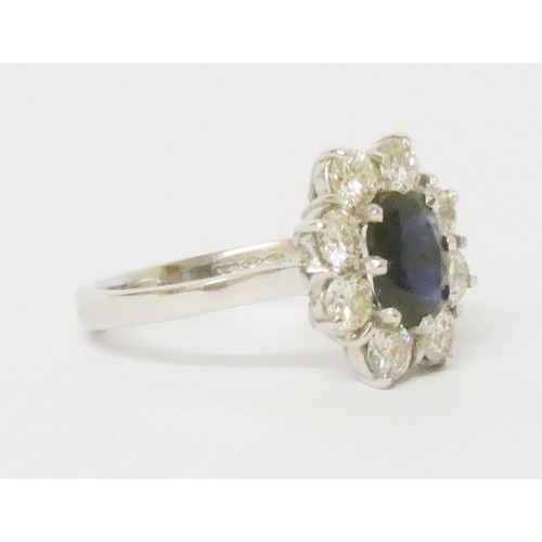 693 - A sapphire and diamond cluster ring, large oval sapphire surrounded by brilliant cut diamonds, on pl... 