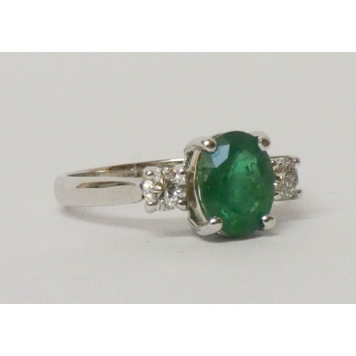 699 - An emerald and diamond three stone ring, set with an oval emerald to the centre on 18ct white gold s... 