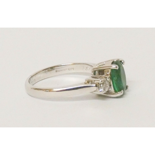 699 - An emerald and diamond three stone ring, set with an oval emerald to the centre on 18ct white gold s... 