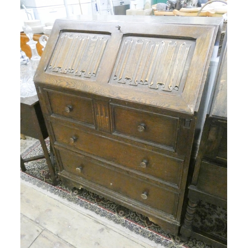 43 - A reproduction oak bureau with linen fold fall and three long drawers under 2'6 wide