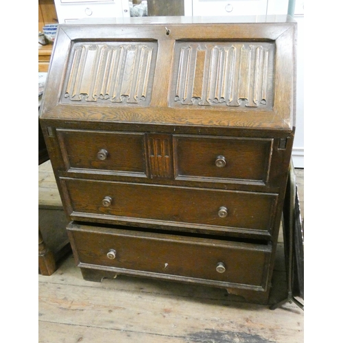 43 - A reproduction oak bureau with linen fold fall and three long drawers under 2'6 wide