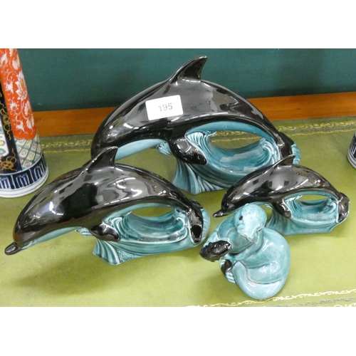 195 - A set of three Poole Pottery dolphin ornaments and a Poole seal ornament