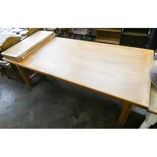 9 - A large modern heavy light oak dining table with two centre leaves, standing on heavy refectory styl... 