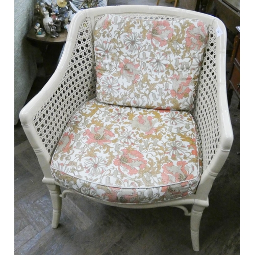 99 - A cream simulated bamboo framed elbow chair with cane panels and floral loose cushions