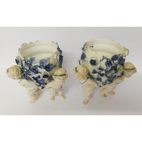 121 - A pair of Dresden porcelain cherub jardinières, decorated in blue and white with rose encrustations