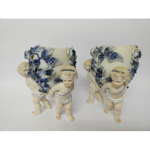 121 - A pair of Dresden porcelain cherub jardinières, decorated in blue and white with rose encrustations