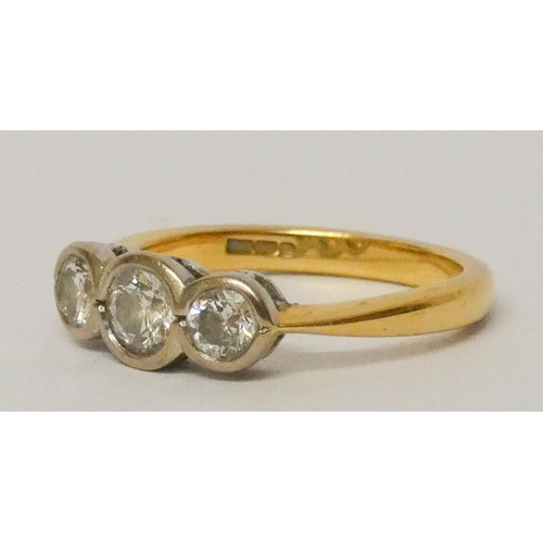 655 - 18ct gold three stone diamond ring, set three circular brilliant cut diamonds in a rub over setting.... 