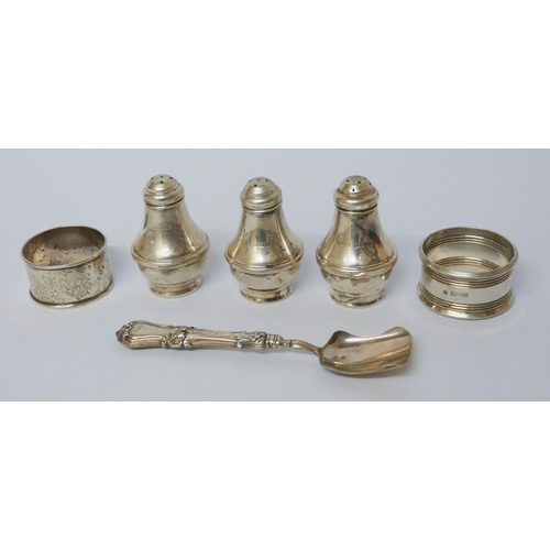 556 - Three silver pepperettes, napkin rings and a jam spoon