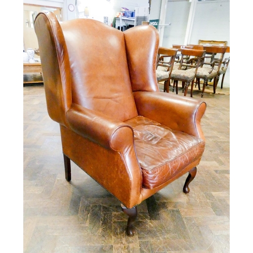 184 - A Georgian style wing backed easy chair in brown leather